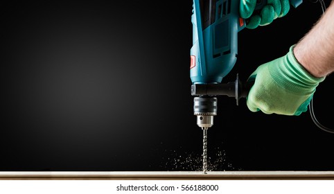 Man in Gloves Drilling wooden plank by Green Drill, close-up. Copy space. - Shutterstock ID 566188000