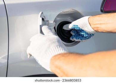 a man in gloves opens the cap of a gas tank of a car. hand holding gas cap. High quality photo