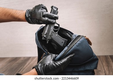 A Man In Gloves Takes A Gun Out Of His Backpack. Seizure Of Weapons And Baggage Search. Crime Concept. The Policeman Searches The Bag. Evidence Of A Crime.