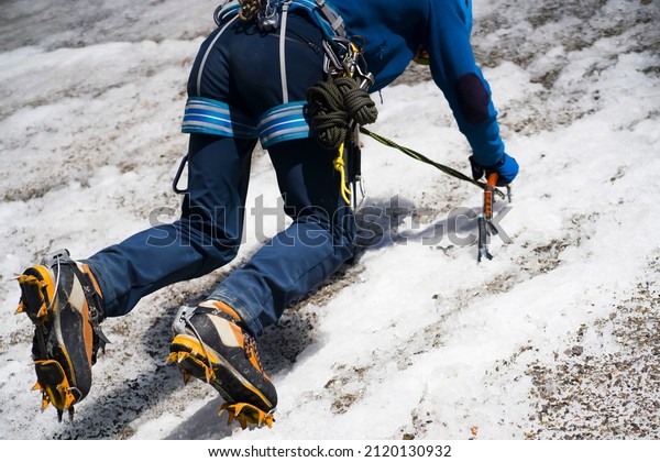 A man goes hiking, winter hiking in the\
highlands, and puts crampons on his climbing boots before climbing\
the glacier and snowy\
mountain.