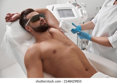 Man with goggles and bare chest undergoes procedure of arm pit laser epilation in clinic - Shutterstock ID 2148429855