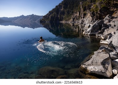 Man Going In For A Swim In Crater Lake NP Oregon In A Beautiful Calm Afternoon, The Cleetwood Cove Trail Leads To The Shore And It Is One Of The Only Places Where Swimming In Allowed.