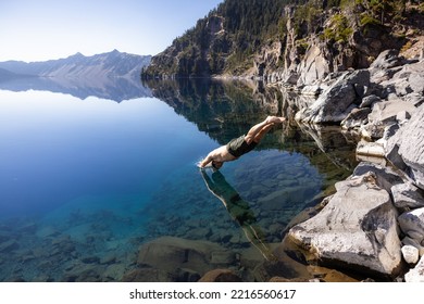 Man Going In For A Swim In Crater Lake NP Oregon In A Beautiful Calm Afternoon, The Cleetwood Cove Trail Leads To The Shore And It Is One Of The Only Places Where Swimming In Allowed.