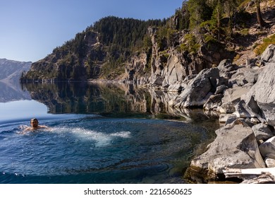 Man Going In For A Swim In Crater Lake NP Oregon In A Beautiful Calm Afternoon, The Cleetwood Cove Trail Leads To The Shore And It Is One Of The Only Places Where Swimming In Allowed.