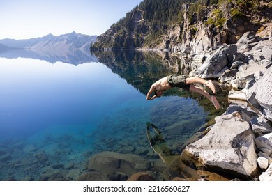 Man Going In For A Swim In Crater Lake NP Oregon In A Beautiful Calm Afternoon, The Cleetwood Cove Trail Leads To The Shore And It Is One Of The Only Places Where Swimming In Allowed.