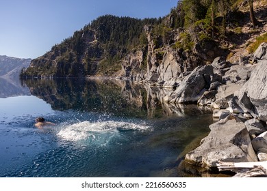 Man Going In For A Swim In Crater Lake NP Oregon In A Beautiful Calm Afternoon, The Cleetwood Cove Trail Leads To The Shore And It Is One Of The Only Places Where Swimming In Allowed.