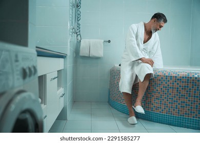 Man is going to take bath, checking water temperature - Powered by Shutterstock