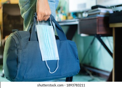 Man Going To Work With Laptop Bag And Protective Mask In Hand. Man With Briefcase And Disposable Face Mask