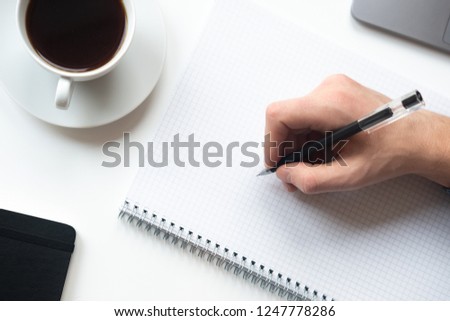 Man is going to write something on the notebook. Top view.