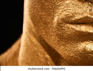 Man In Gold Paint. Detail Of A Man's Face Courageous Lips, Neck And Chin.
A Handsome Man Of Athletic Build, Completely Covered In Gold Paint.