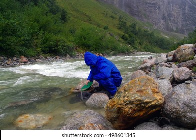 A Man Gold Panning In A River With A Sluice Box