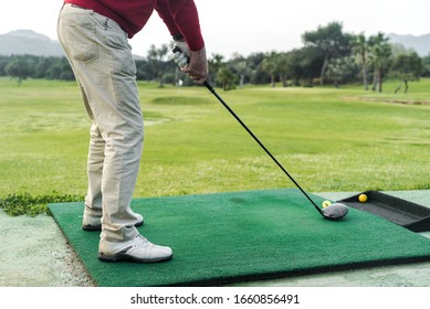 Man at the golf shooting range about to shoot with his ball. Golf in Spain. Sports enthusiasts of golf.