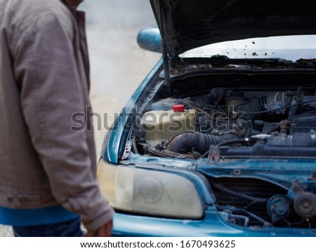 The man got a problem with the car. Boiling water in the engine of an old car.