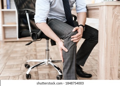 The man grabbed his knee and feels severe pain. A man in the office does a knee massage to relieve acute pain.