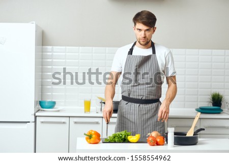 Man in gray aprons cutting vegetables kitchen apartment building cooking meal