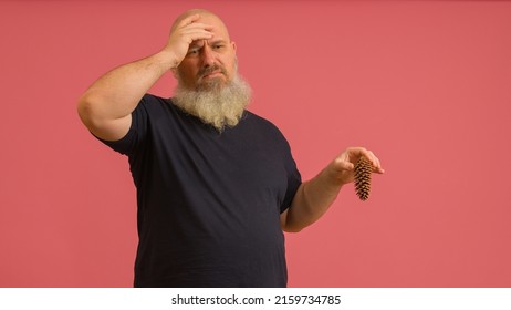 A man with a gray beard with a bump in his hand holds his head on a colored background. The concept of male potency. - Shutterstock ID 2159734785