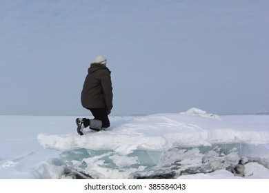 The Man In A Gray Cap Sitting On An Ice Block Looking Afar