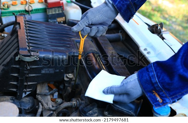 \
A man in gray gloves holds\
the oil dipstick to check the engine oil. under the concept of car\
maintenance , focus on the right hand holding the oil gauge\
rod