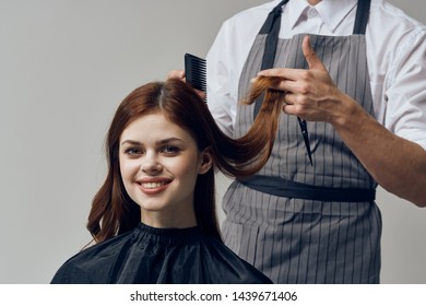 A man in a gray partaki barbershop hairbrush scissors hairstyle young woman black peignoir smile                