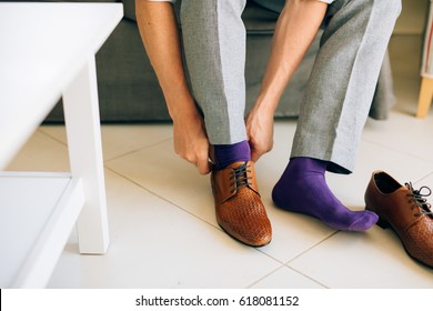 The Man In Gray Slacks And A Purple Dress Socks Brown Shoes With Laces Sitting On The Couch.