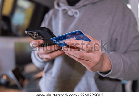 man in a gray suit standing and holding a credit card and using a laptop on the table to buy online or subscribe to some service. young businessman using internet while teleworking. electronic banking