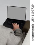 Man in a gray sweater with a laptop, front view, macbook mockup