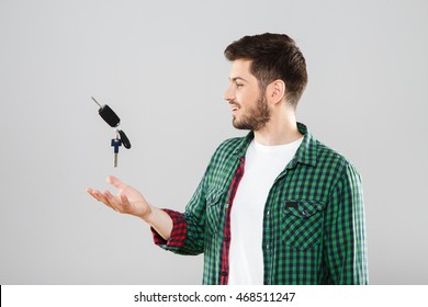 Man In Green Checked T-shirt Throwing Up Car Keys. Looking At Keys. Waist Up, Profile. Indoors, Studio