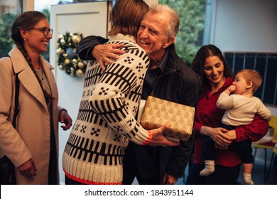 Man greeting and hugging his father at front door. European family coming together for Christmas festive celebrations.
