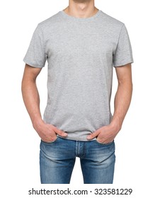 A man in a grey t-shirt and denims holds his hands in pockets. Isolated on white.