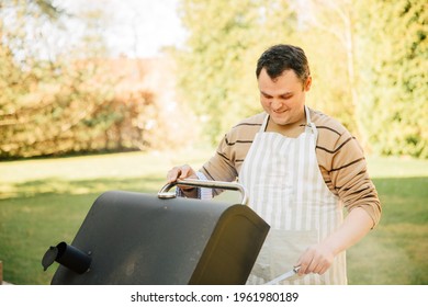 Man Grilling With Belly In The Garden. Barbecue At Home When The Weather Is Nice. Prepare Food Outside 