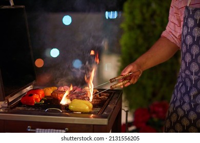 a man is grilling the food on bbq on the patio at summer evening - Shutterstock ID 2131556205