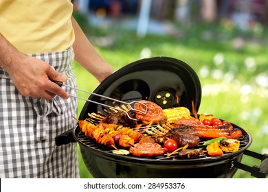 Man Is Grilling Meat On Barbecue For Family Dinner