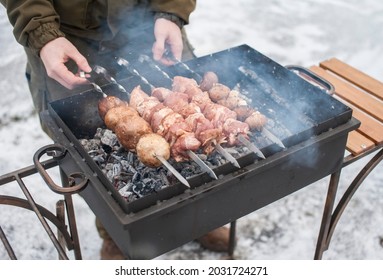 A man grills meat and mushrooms in winter. close-up. Winter picnic, outdoor recreation 
