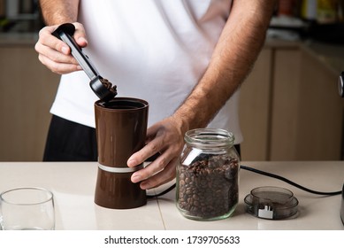 Man grinding coffee beans for making an espresso. Home barista indoors lifestyle concept