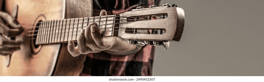 Man guitarist plays in a plaid shirt. Play the guitar. Guitars and strings. Male playing guitar, holding an acoustic guitar in his hands. Music concept. - Powered by Shutterstock