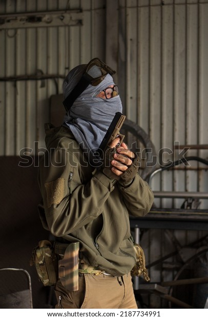 A\
man with a gun with a hidden face guards a\
warehouse