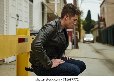 A Man With A Gun Out Back Waiting For Someone, A Car In The Background Coming His Way. 