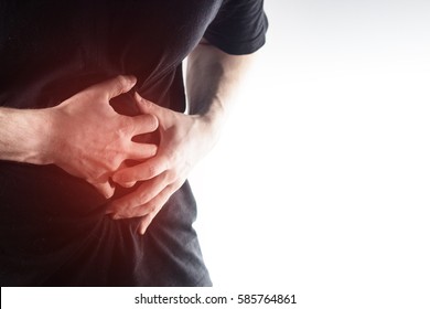 man, guy in a black t shirt on a white background hold hands on his stomach,  liver pain, pancreas, kidneys  - Shutterstock ID 585764861
