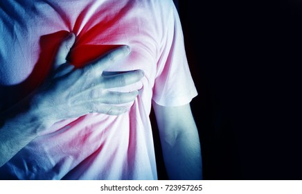 man, guy in a white t shirt on a black background in a blue color hold hands on his heart, heart atack, severe heartache, chest  myocardial infarction