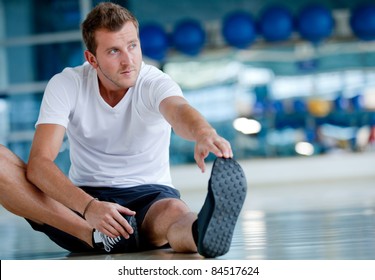 Man At The Gym Doing Stretching Exercises And Smiling On The Floor