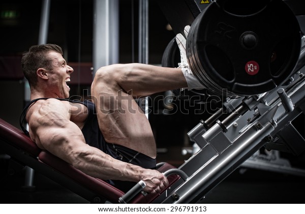 Man in gym training at leg press to define his\
upper leg muscles