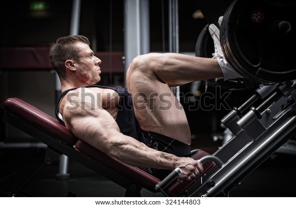 Man in gym training at leg press to define his\
upper leg muscles