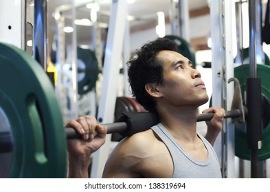  Man Gym Workout, Using A Squat Machine At Fitness Club