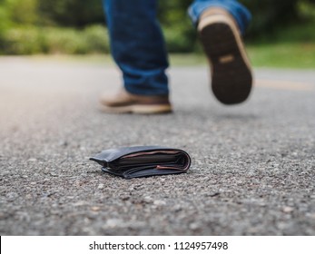 The man had lost leather wallet with money on the street. Close-up of wallet lying on the road concrete sidewalk. Lost money concept.