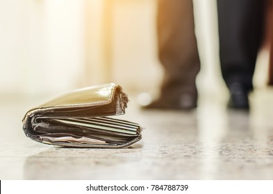 Man had lost leather wallet with money on the floor. Close-up of wallet lying on the sidewalk and feet of outgoing man