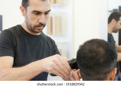 A man at the hairdresser's while his hair is being cut and an electric razor