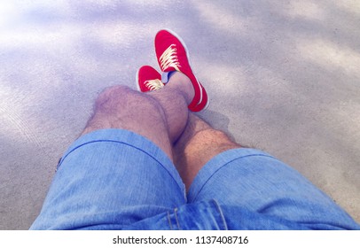 Man With Hairy Legs In Denim Shorts And Red Sneakers