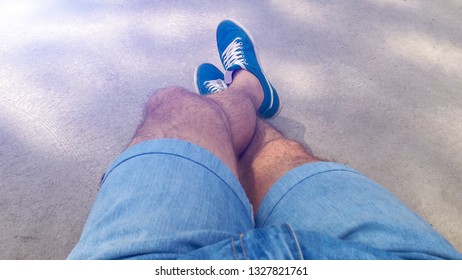 Man With Hairy Legs In Denim Shorts And Blue Sneakers