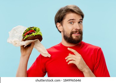 Man with hamburger in his hands fast food diet red t-shirt blue background 