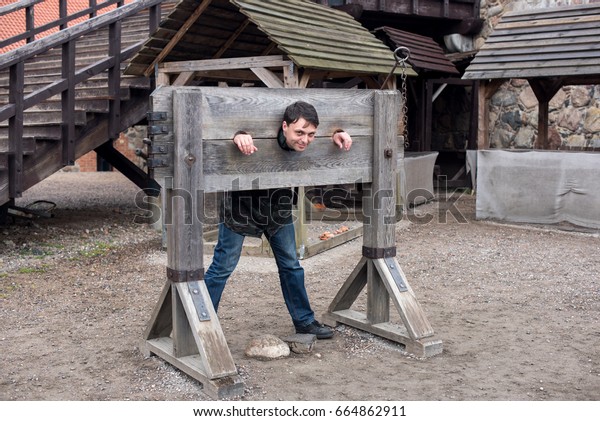 A\
man hammered out by middleage torture device -\
pillory